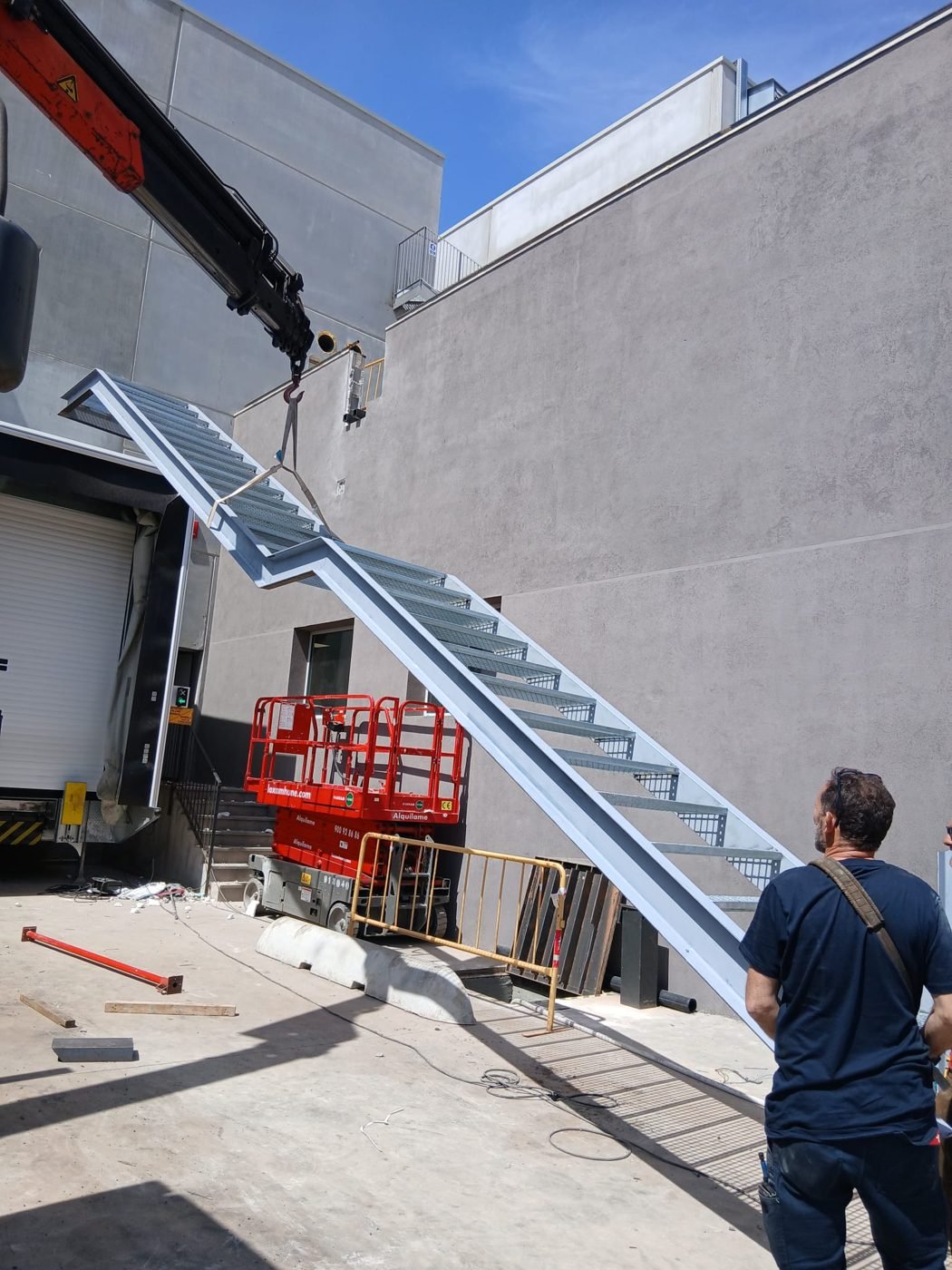 Montaje de una escalera metálica con grúa en obra