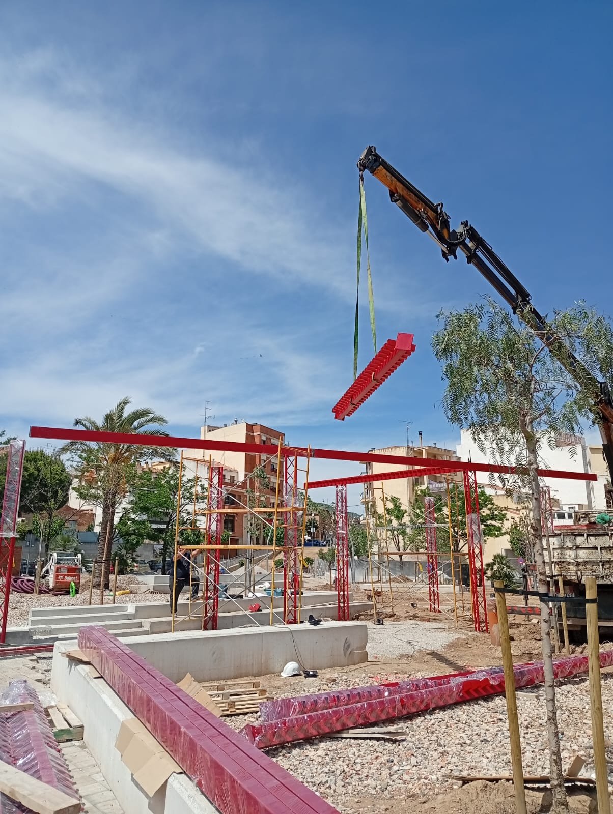 Viga de acero roja suspendida por la grúa sobre la estructura en obra